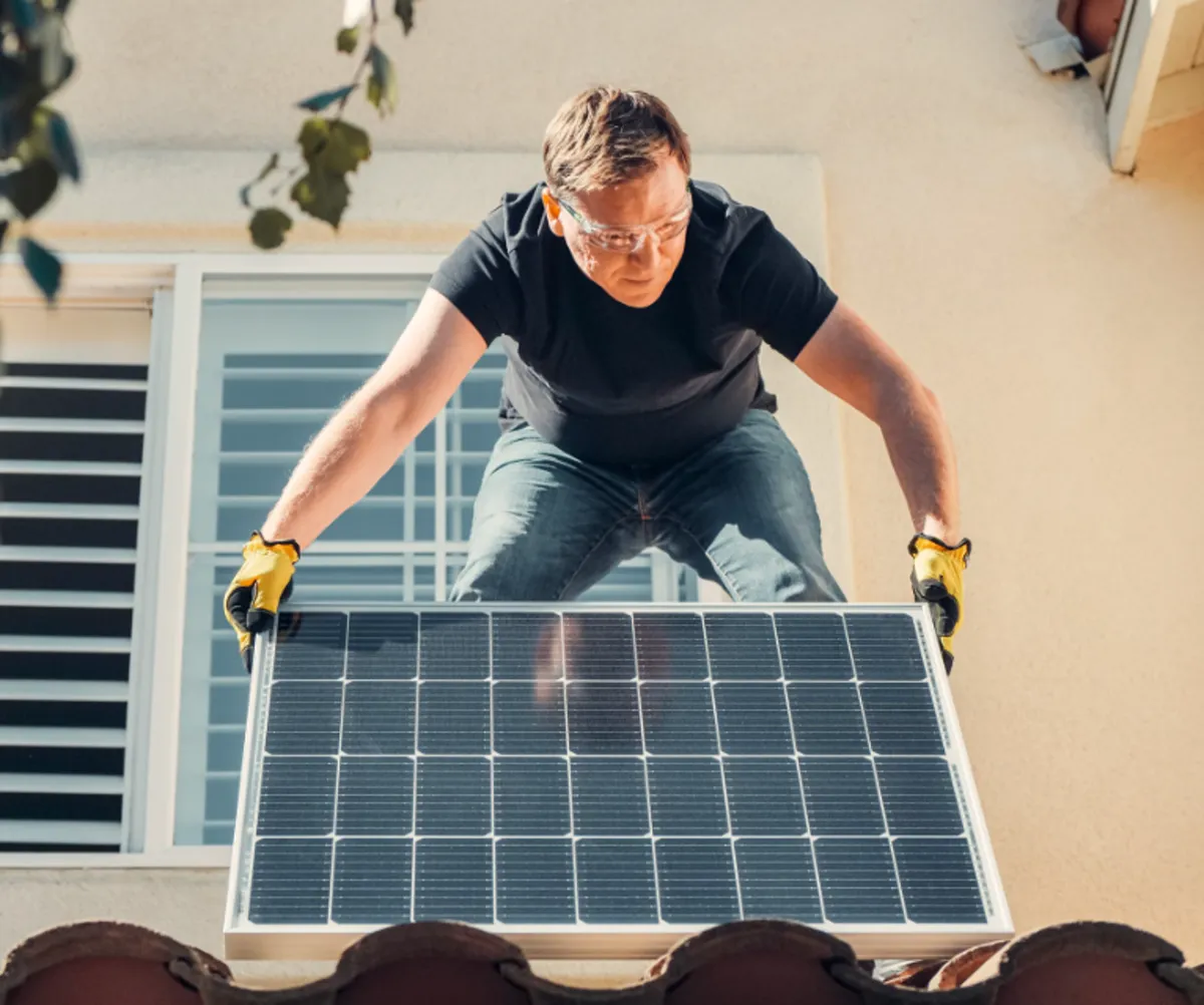 Instalador colocando una placa solar en el tejado de una vivienda