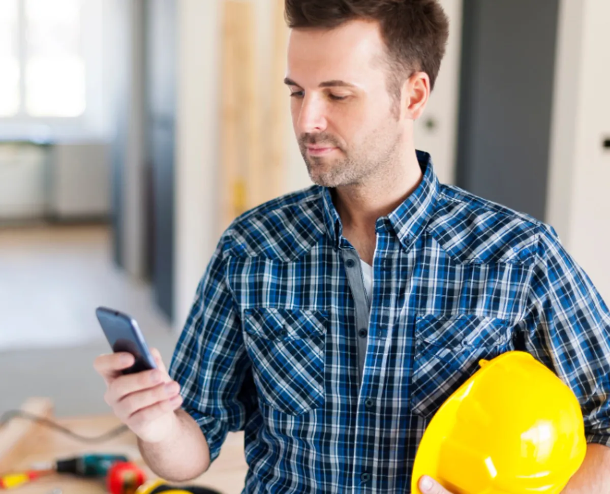 Profesional de la construcción consultando trabajos disponibles en el móvil